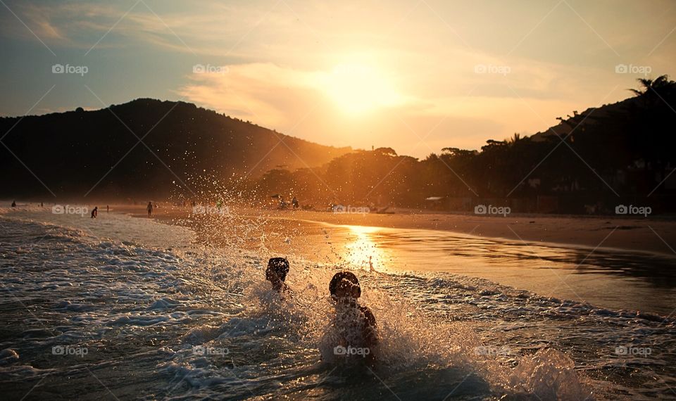 Kids playing on the sea at sunset