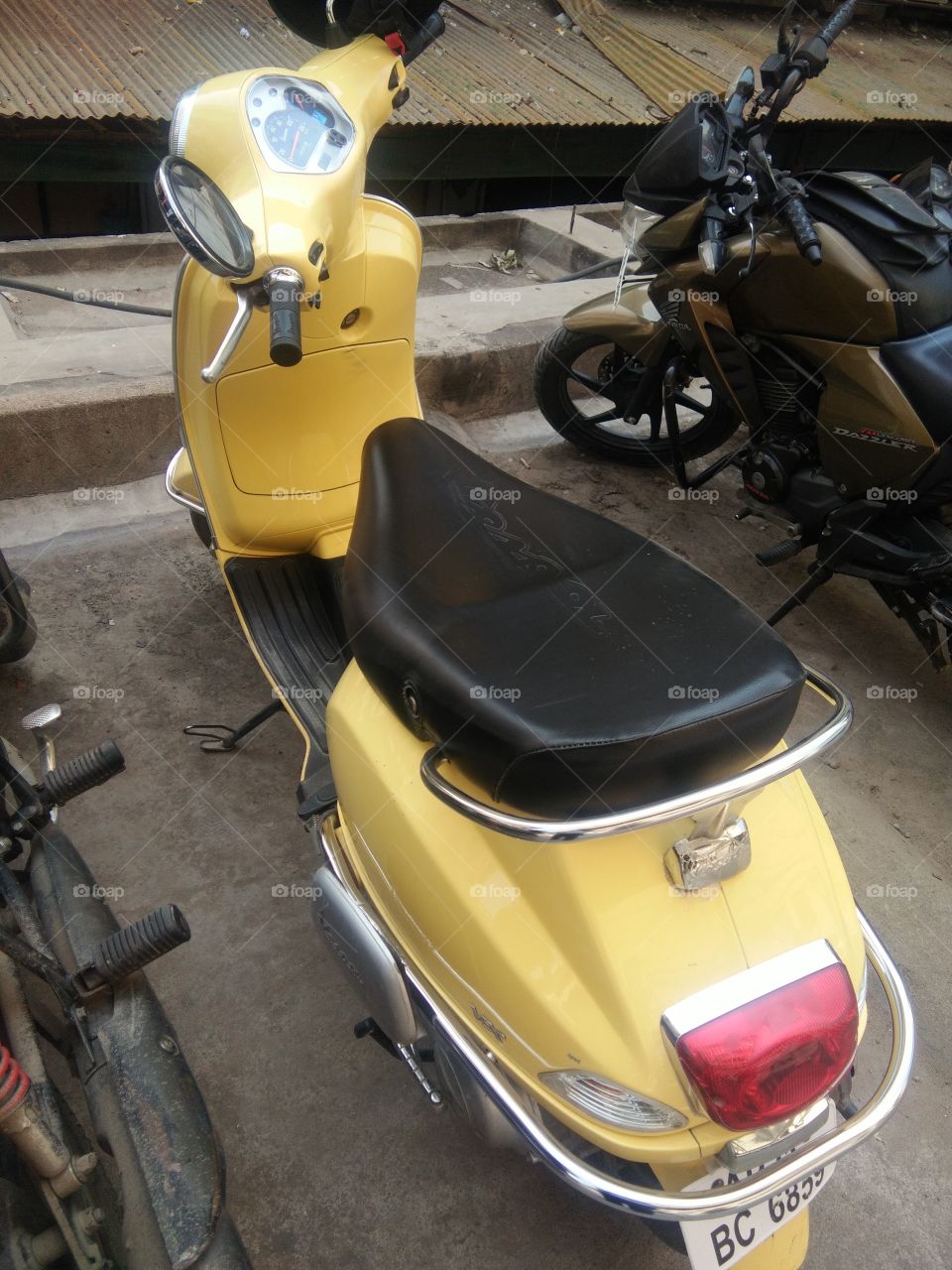 Two wheeler yellow vehicle parked outside the building..