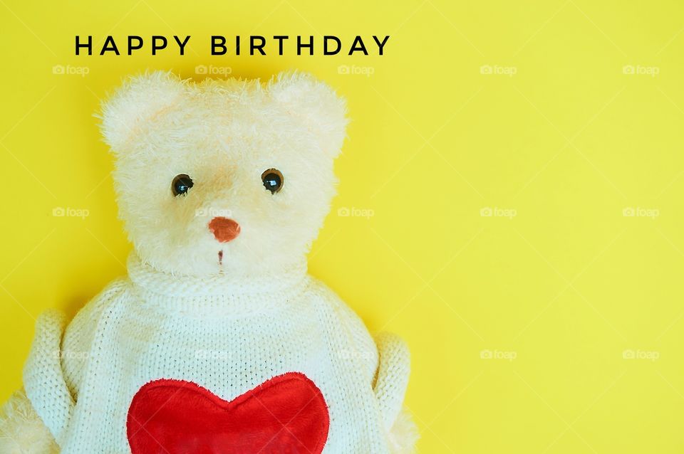 Happy birthday with teddy bear on yellow background 