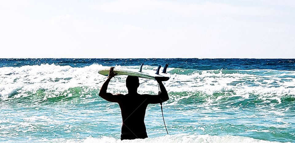 surfer headed out it sea.