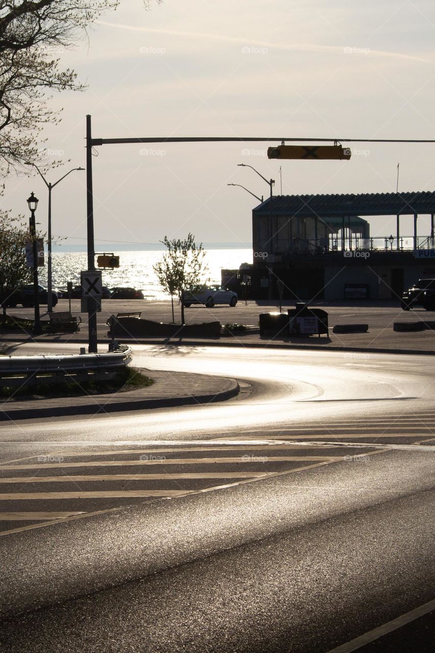 City road curving around a corner with a lake in the background in the spring at sunset