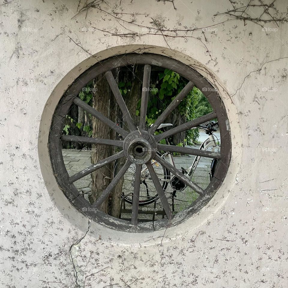 An old carriage wheel embedded in the wall, through which you can see. 