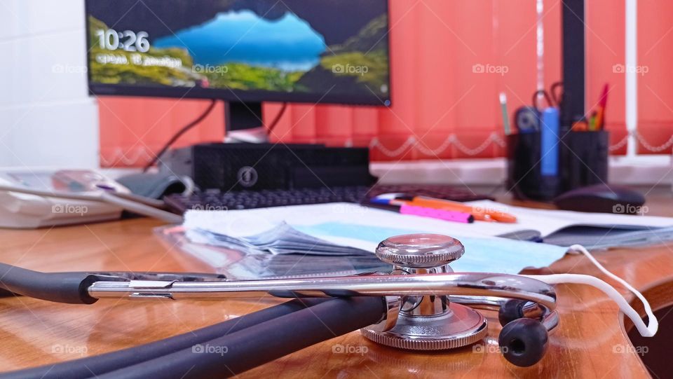 Doctor's desk, computer desk,monitor, blinds, orange,magazines,pens,phonendoscope,medical mask,doctor's office, reception room