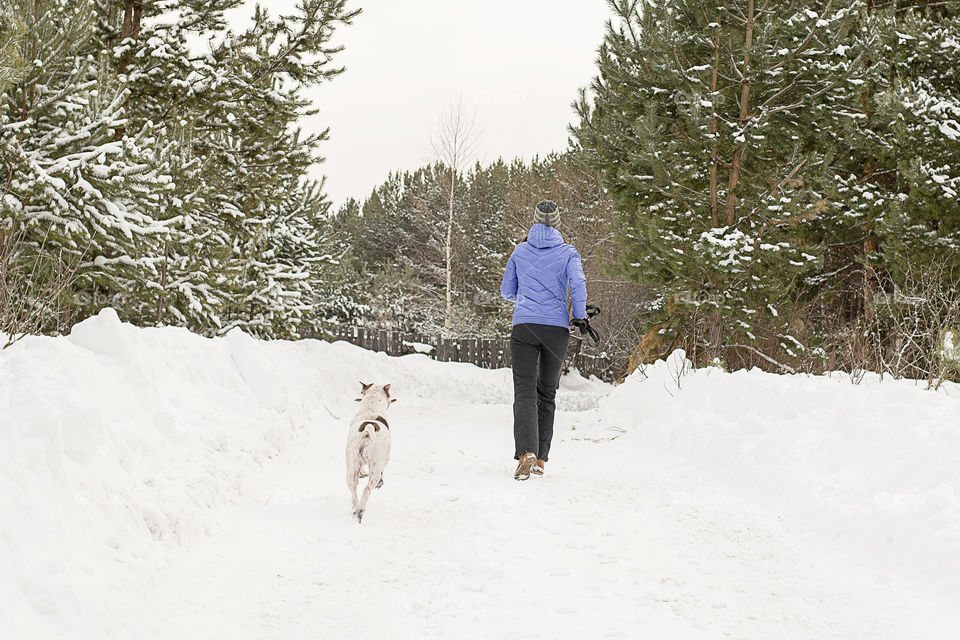 girl with dog running from snow road
