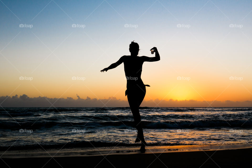 Woman dancing with a drink in the sunset in Jamaica