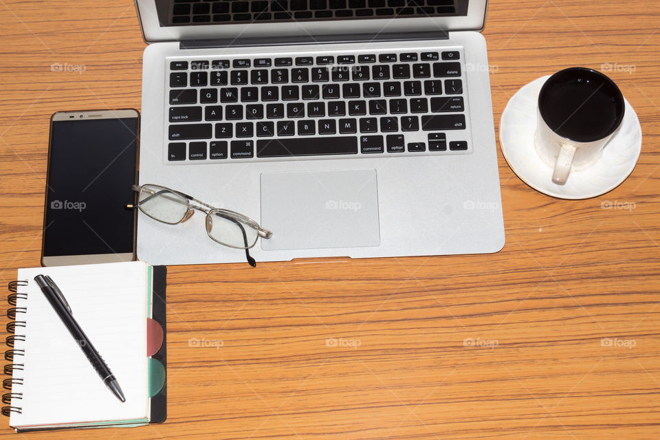 Desk with open notebook, mobile phone, eye glasses, pen and a cup of coffee. Top view with copy space. Business still life concept with office stuff on table. Education, working or planning concept