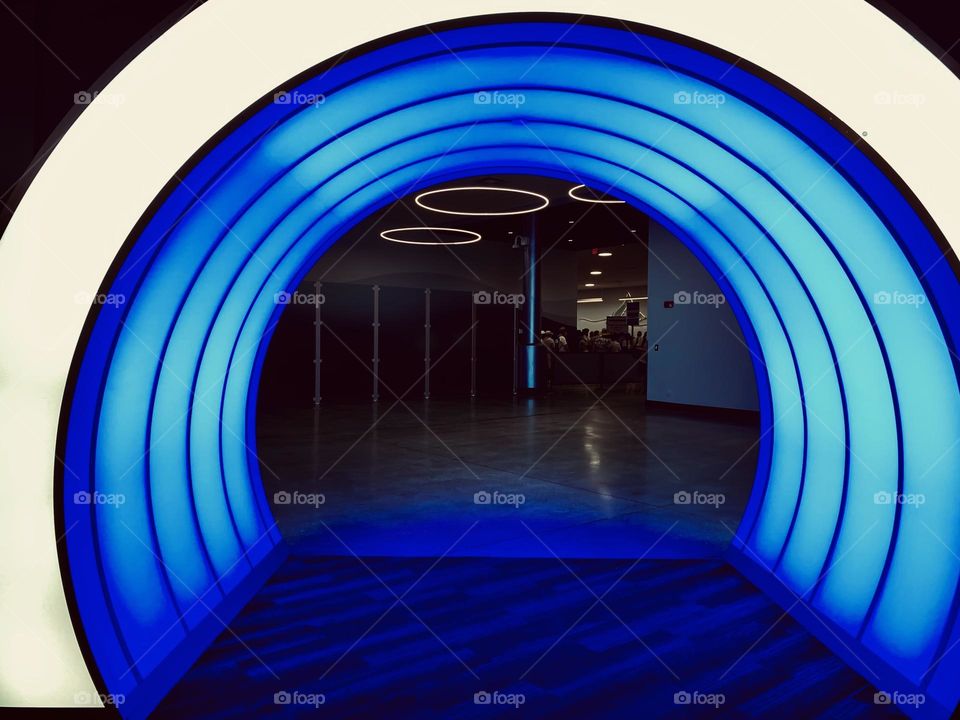 An illuminated round archway between two rooms with circular lights on the ceiling