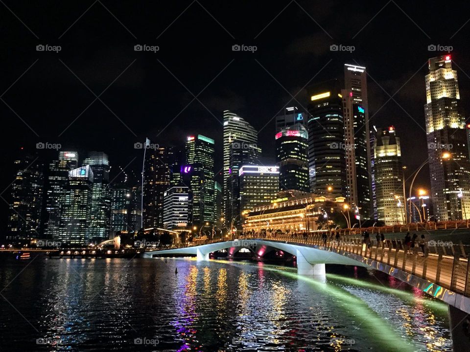 Urban nature - water: night cityscape with skyscrapers, bridge and reflection in the river water channel 