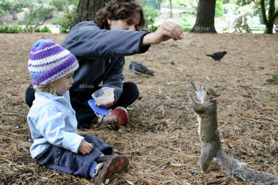 Father and sun feeding squirrel in the park