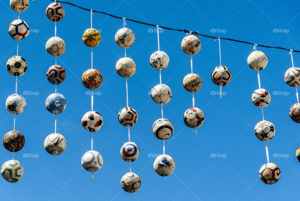 Soccer balls hanging on string over street