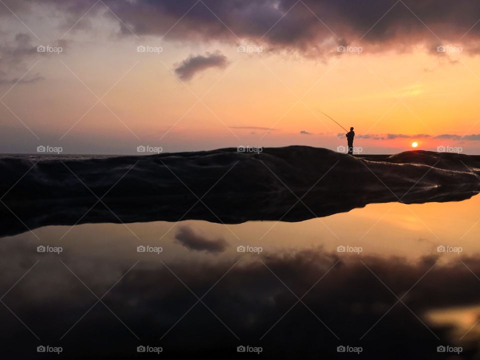 Fisherman silhouette at the sea. 