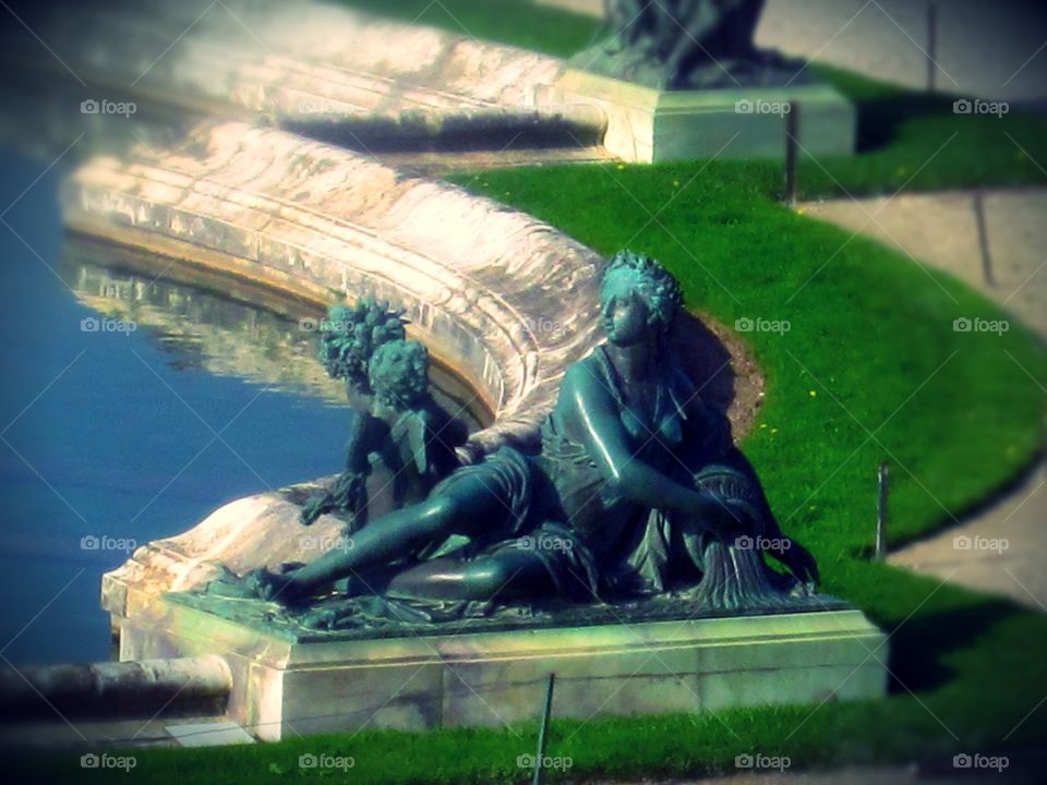 Palace of Versailles and one if it's many statues outdoors.