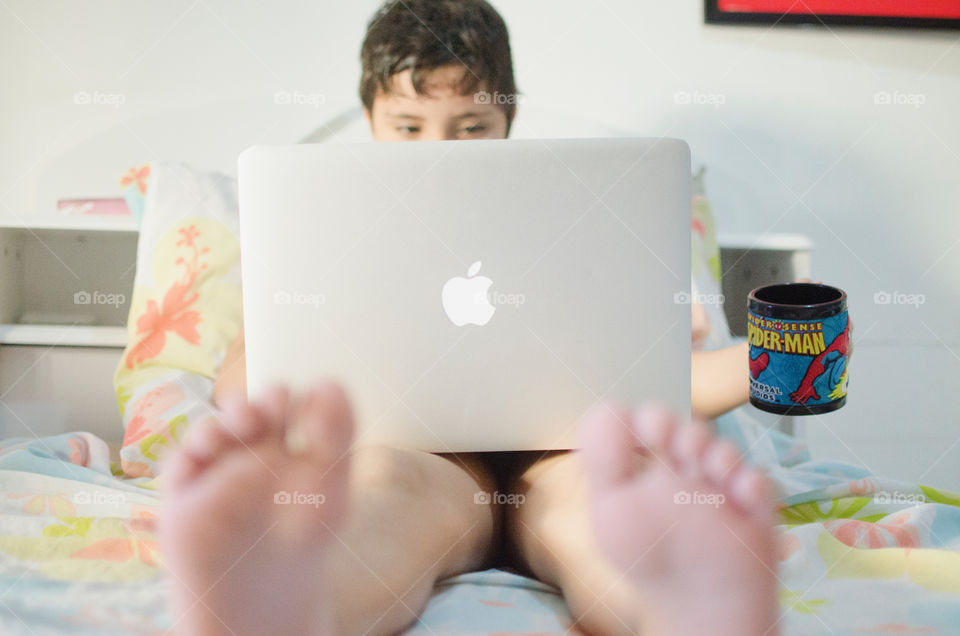 Boy using the computer and drinking a cup of coffee 