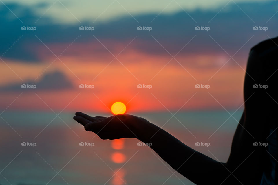 silhouette of human hand holding the sun
