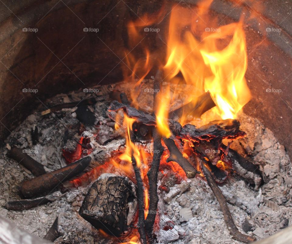 fogón se ve los palos y la ceniza y el fuego