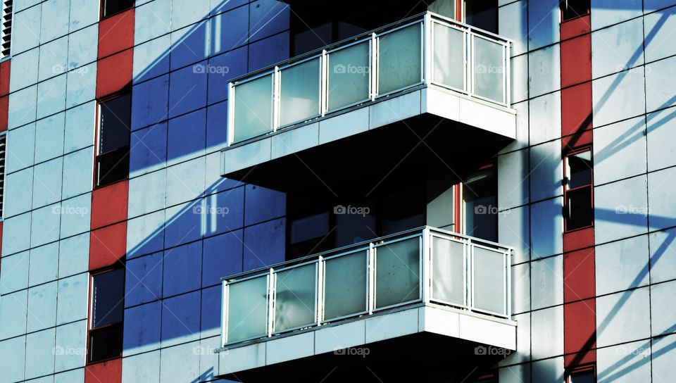 Two balconies one positioned just above the other on a luxury apartment building in New York city off the BQE casts two shadows.