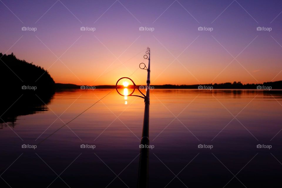Sunset on a lake in Finland seen through a fishing rod ring on a warm and serene summer evening. 
