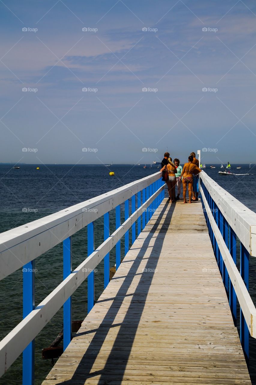 Summer day on the jetty. People on a long jetty out in the sea 