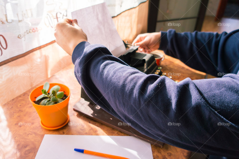 A young writer is writing his new book on his old typewriter.