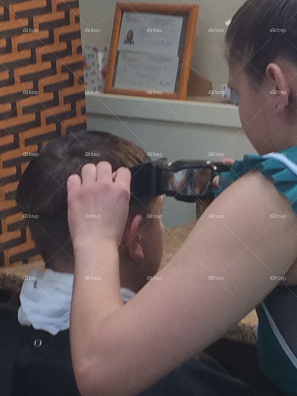 Person cutting hair of a boy with electric razor