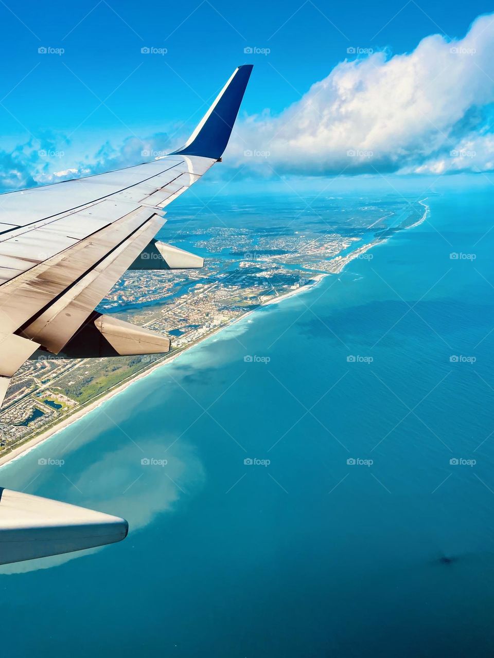 An airplane view of a beautiful turquoise ocean of the Florida shore