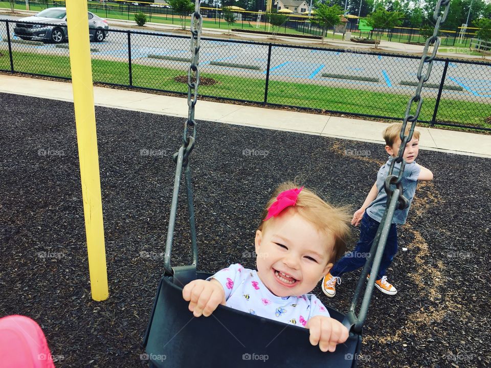 Sibling playing in park on swing