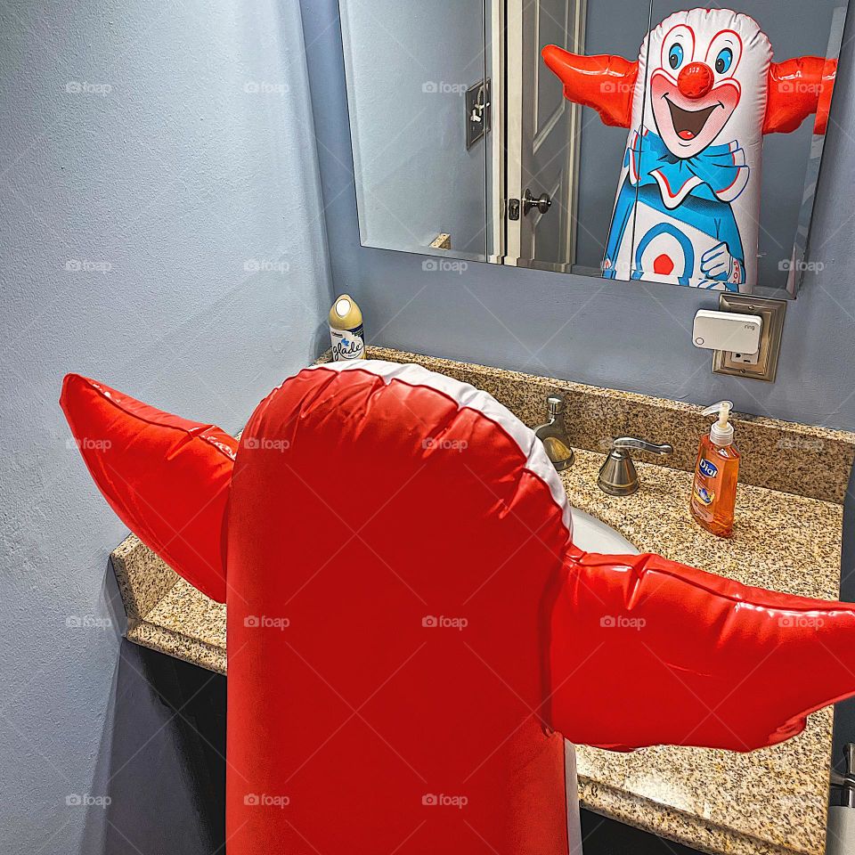 Bozo the clown looking at reflection in the mirror, clown reflections in the mirror, not ordinary reflections in a mirror, clown surprise in the mirror, silly clown reflections