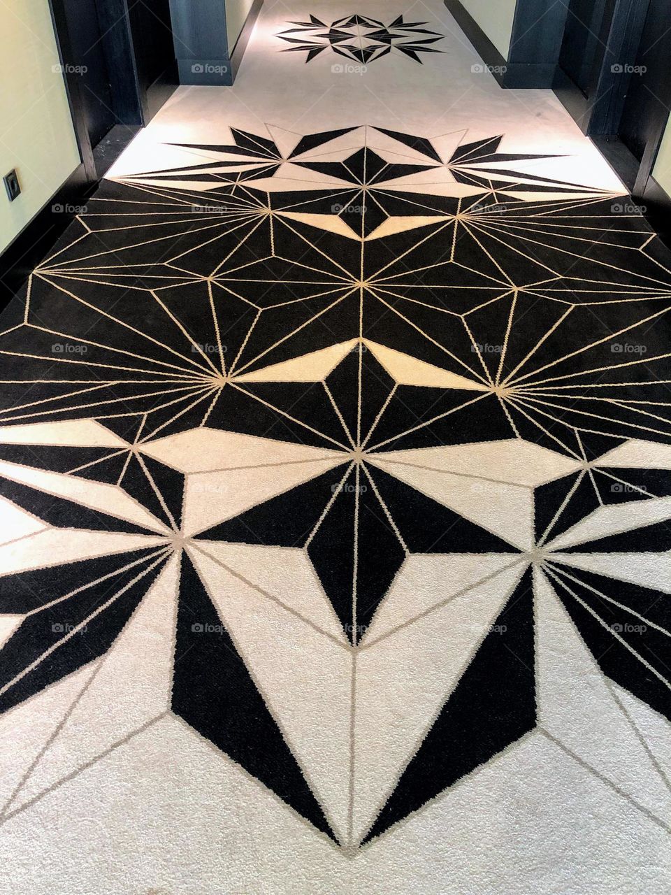 Perspective view to the hotel corridor black and white carpet with triangle shape pattern 