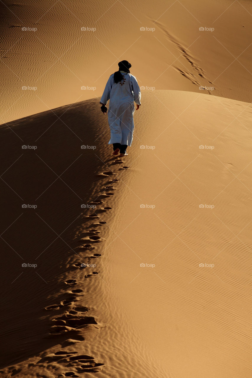 Berber Arab walking up a sand dune