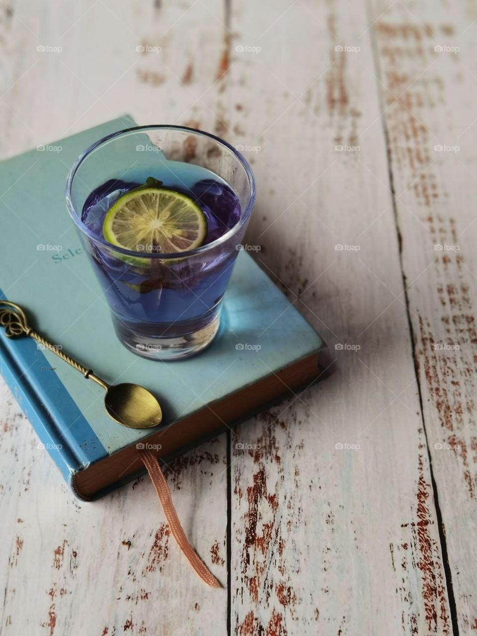 Butterfly pea tea in blue colour and a slice of lemon in a cup in a blue book