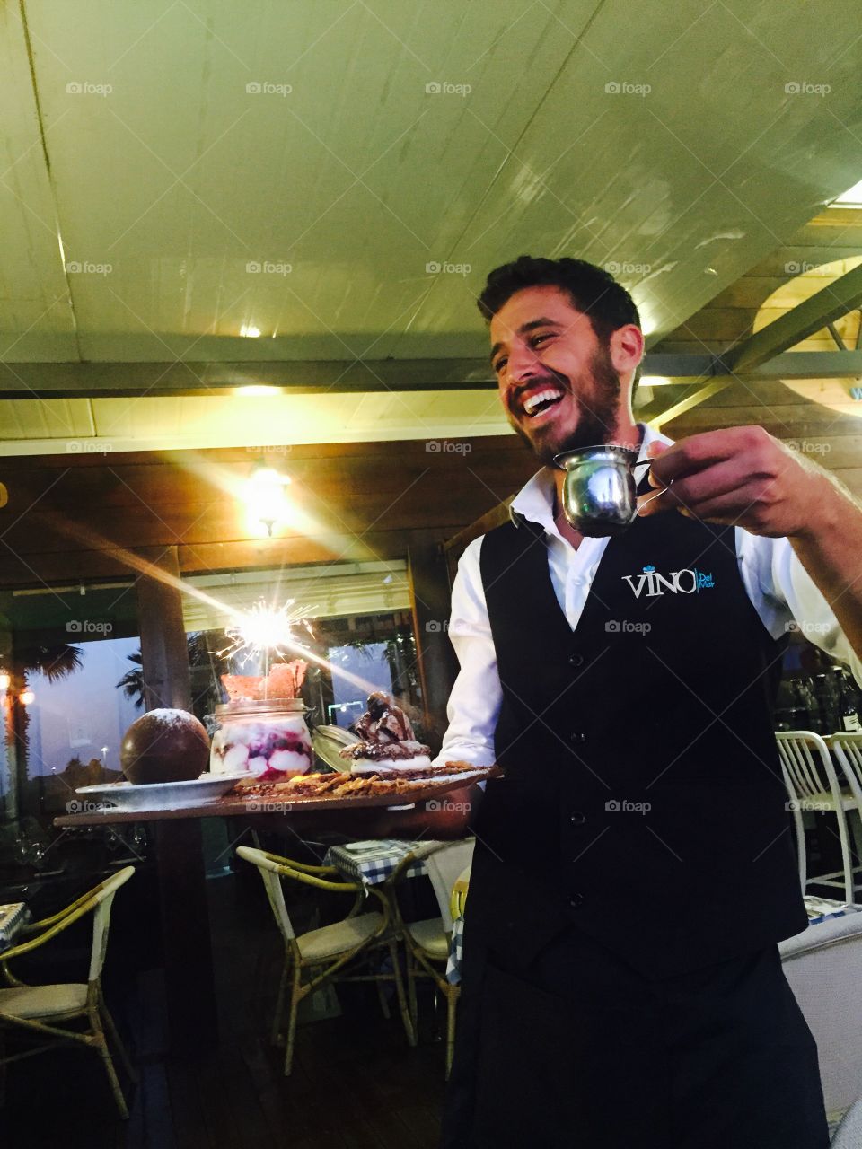 Smiling waiter holding dessert food in hand