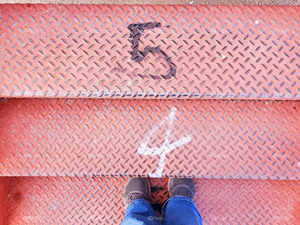 Pink metal stairs with the numbers five and four. Three steps.