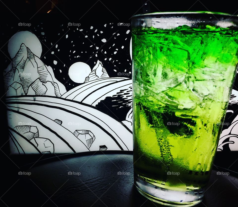 Bright Green mixed drink in front of galactic landscape 