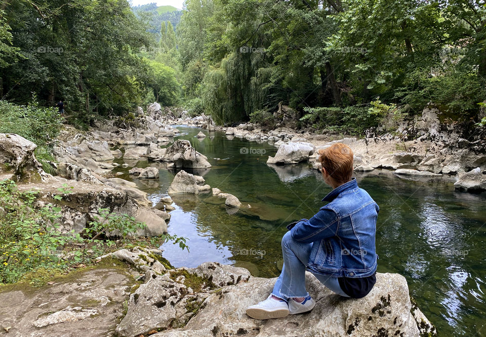 Woman sitting on the riverbank 