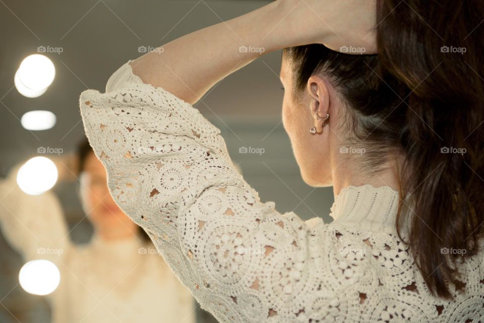 The girl stands in front of the mirror and examines her earrings.  decorations  .