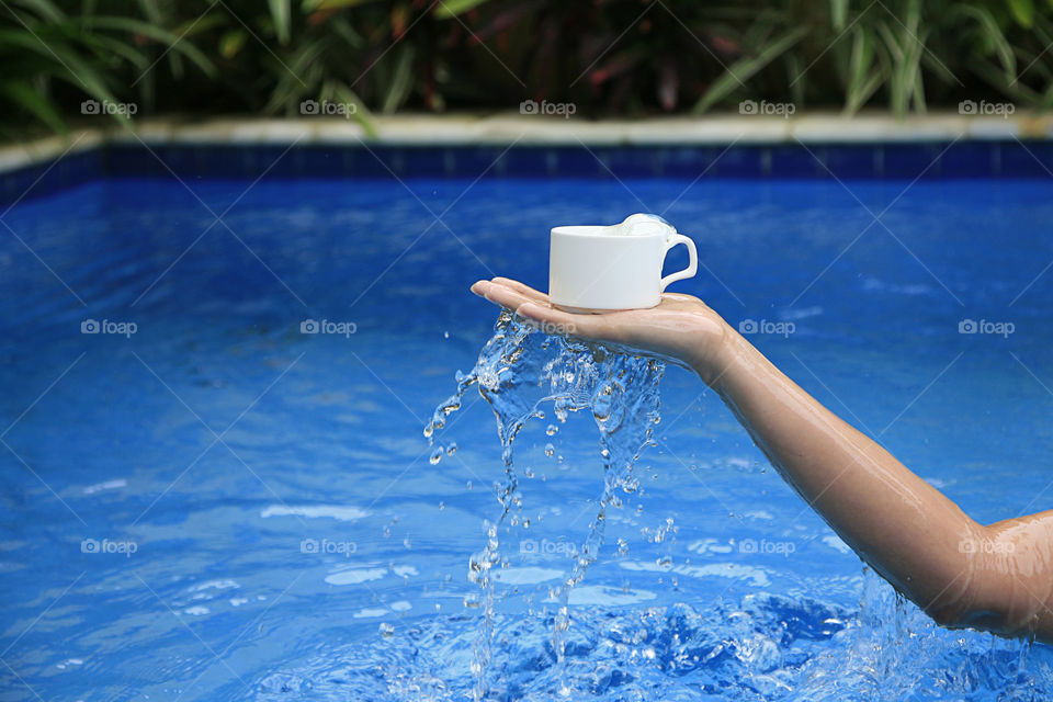 Young woman standing in pool with water. Girl scooping pool water.