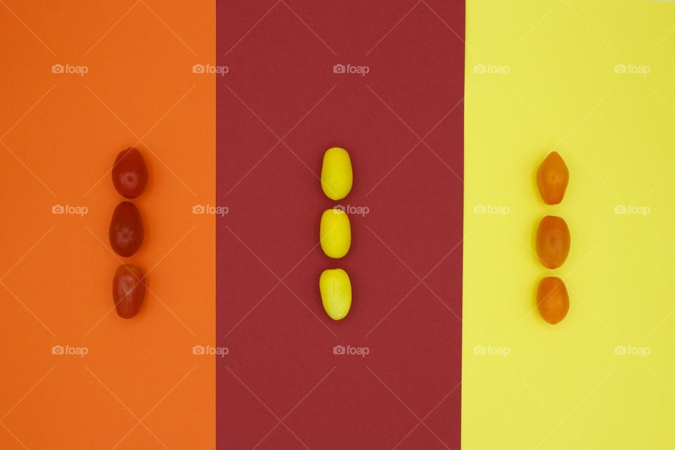 Color Love - flat lay of heirloom medley cherry tomatoes in red, yellow and orange, arranged vertically in threes on orange, red and yellow paper