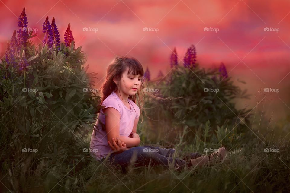 Little girl in blossom field at sunset 
