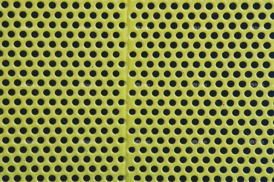 A closeup abstract of a green perforated metal trash container.