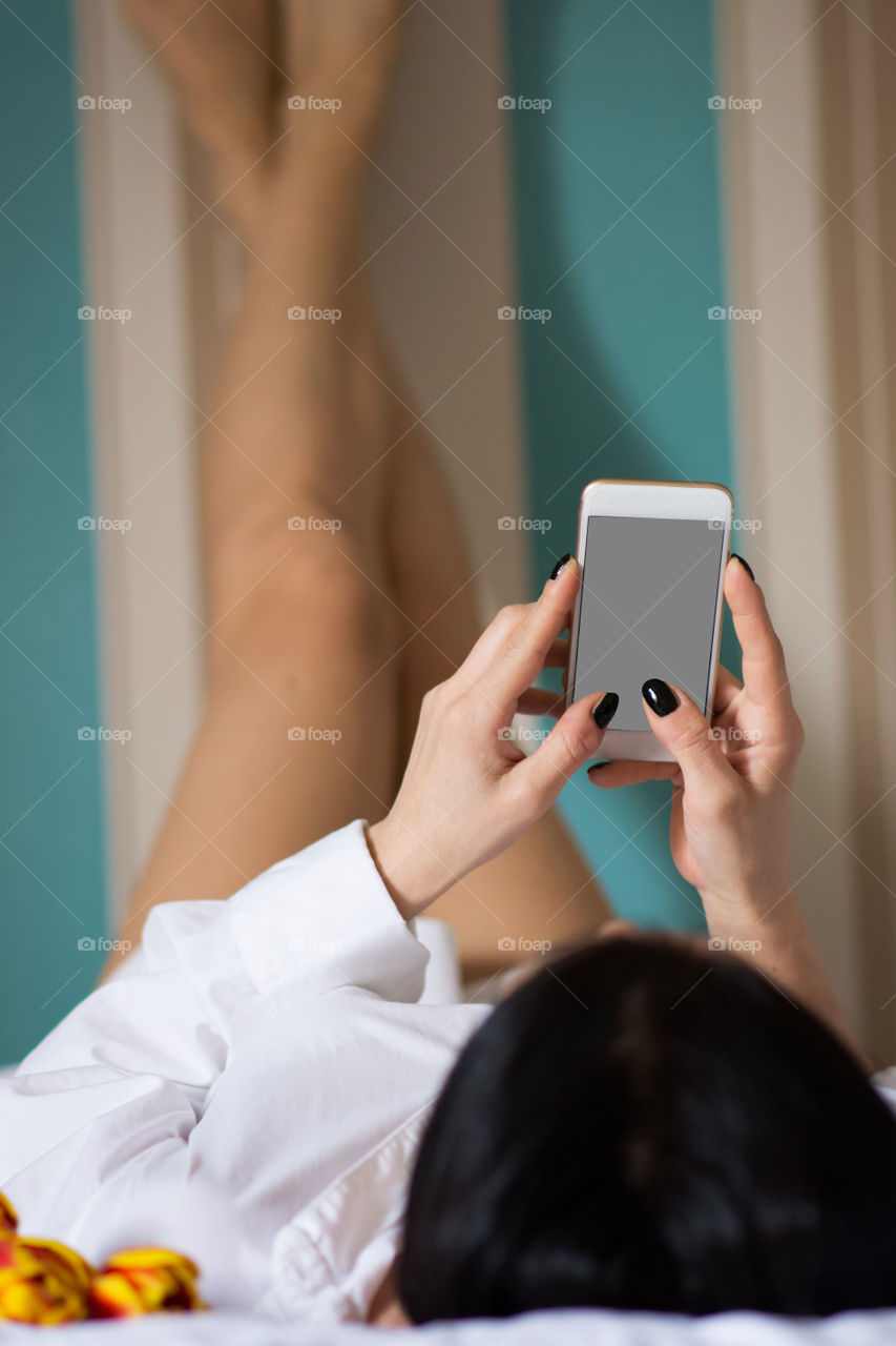 Woman in bed using phone