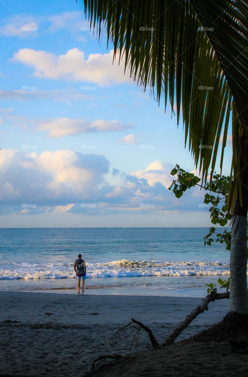 A little moment of happiness.  A young man stands on the seashore and enjoys the beautiful view