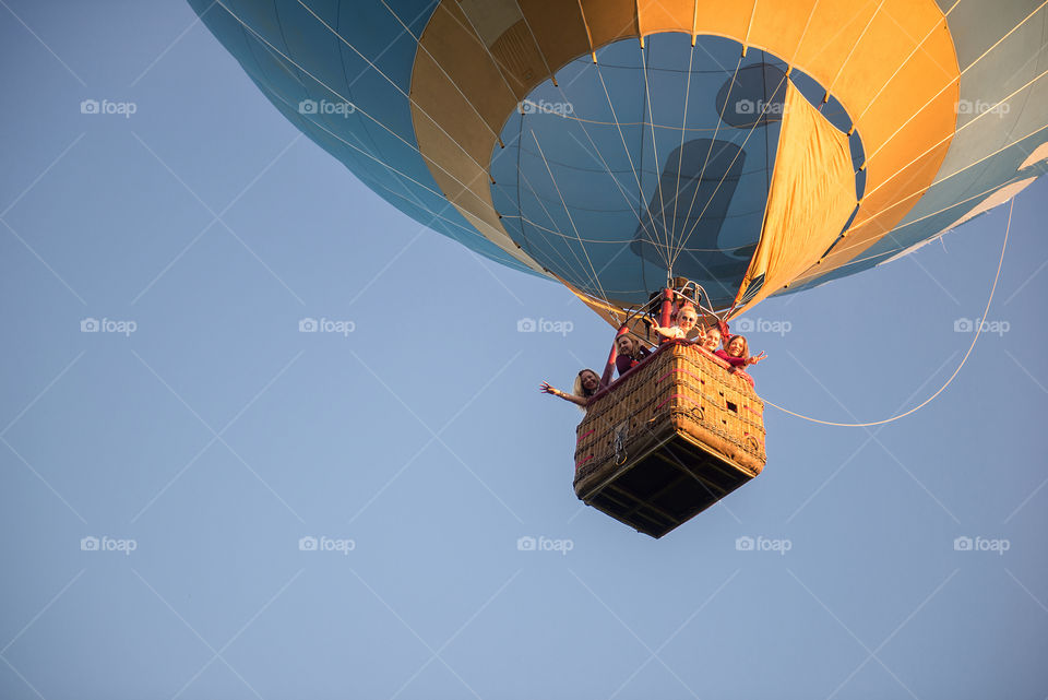 Happy family people in hot air balloon basket on blue sky background