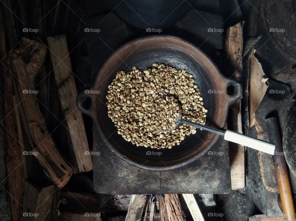 roasting the coffee beans with traditional  kitchenware. using pottery as the frying pan on the fireplace