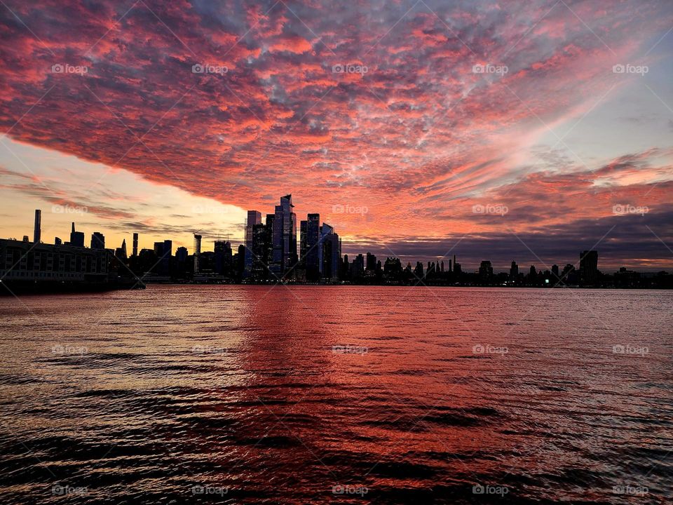 As a weather front moves in over Manhattan a beautiful sunrise glows in pinks and reds as seen from across the Hudson River