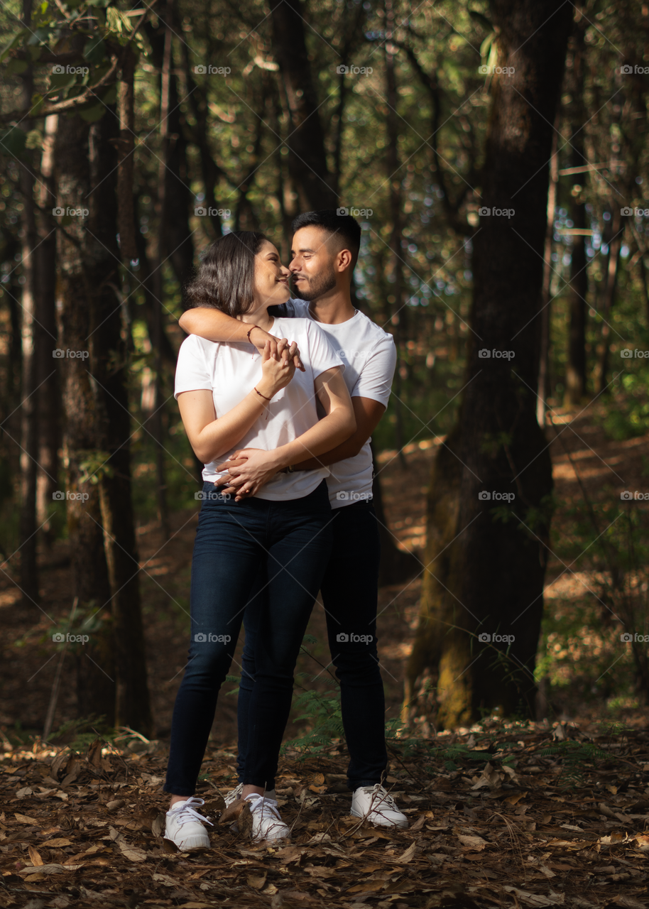 Couples of young people sitting in middle of the forest while looking into their eyes in lovely way, in a sunny day.