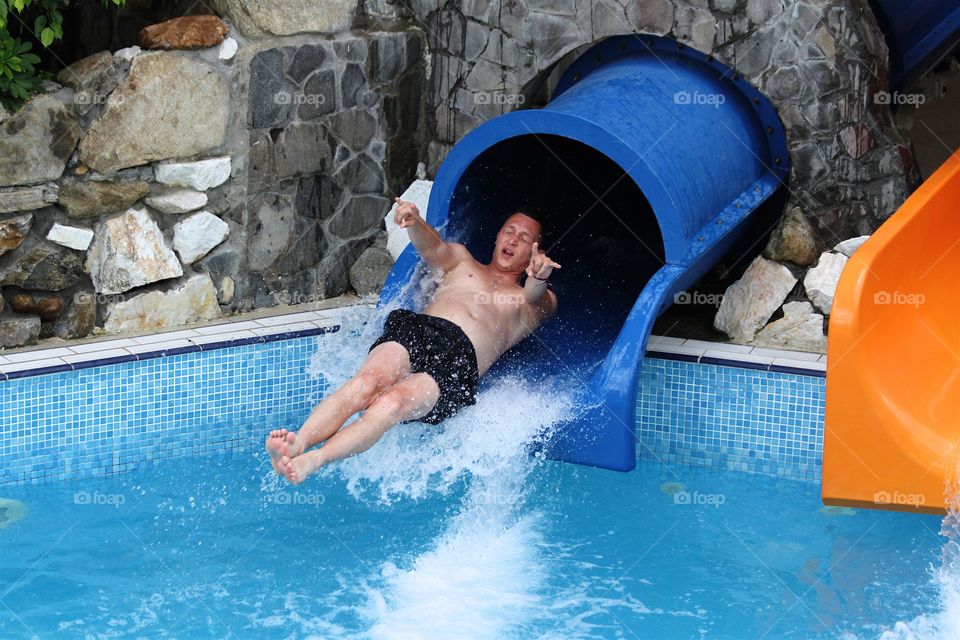 Young man on swimming pool water slide