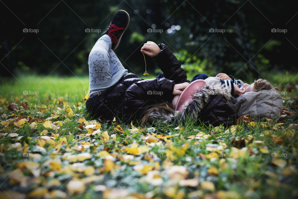 siblings enjoying fall. brother and sister enjiying fall in park laying on grass