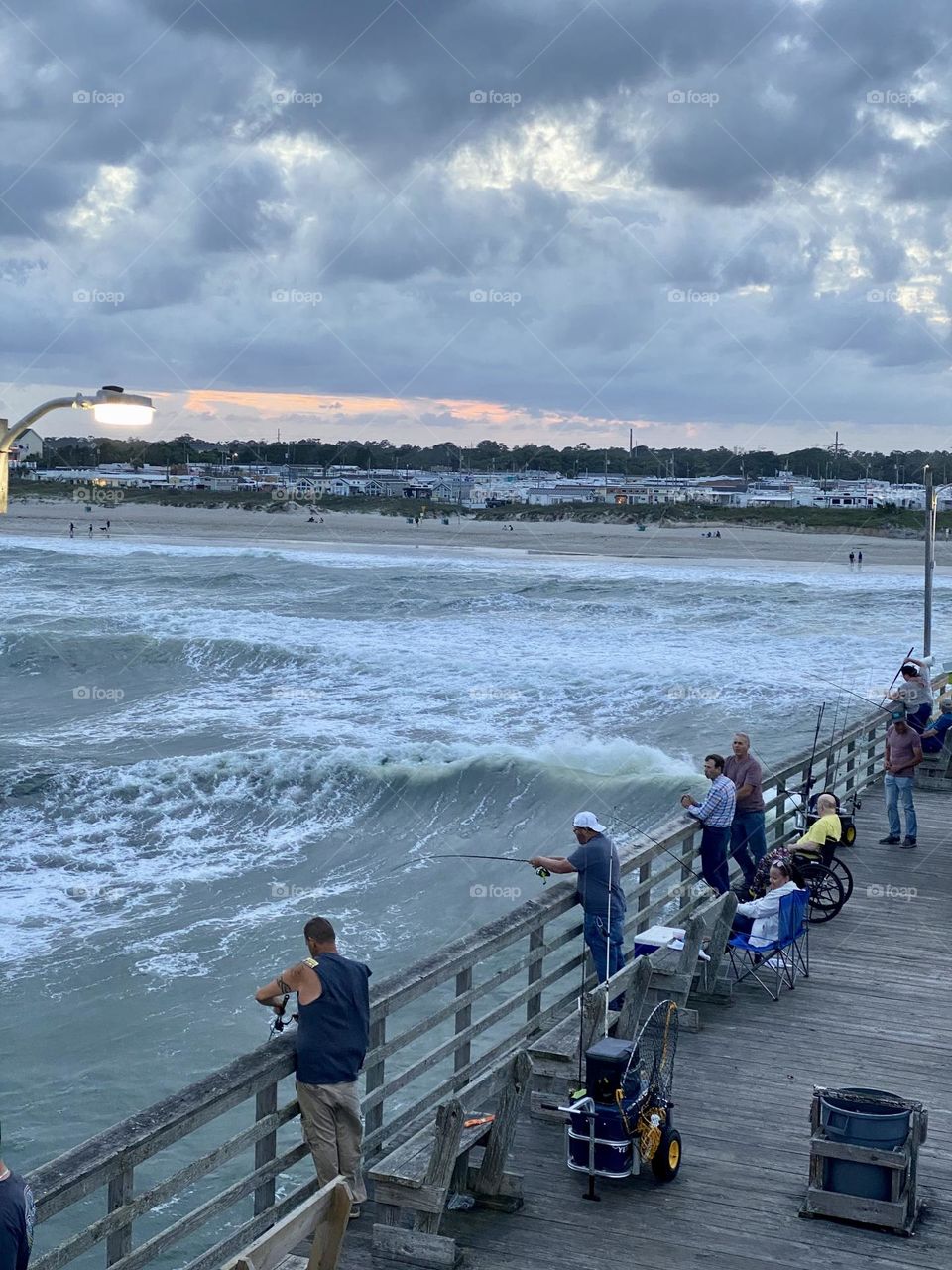 Fishermen fishing off of beautiful North Carolina peer and tourists taking in the gorgeous scenery. 