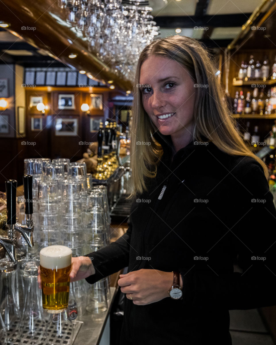 Young woman bartender with a beer