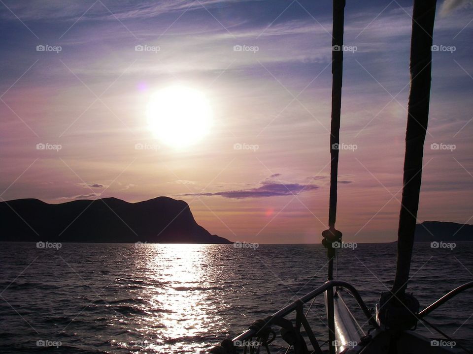 sailing to an island at sea with a sunset